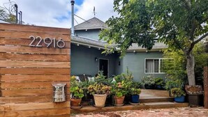 A house with a wooden gate marked '22916,' a brick driveway, and various potted plants. - European Style b&b in Topanga (Topanga)