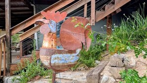 A rustic outdoor setting with a large metal rooster sculpture, a wooden staircase, and a stone wall. - European Style b&b in Topanga (Topanga)