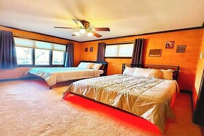 Une chambre d’hôtel avec deux lits, un ventilateur de plafond et de grandes fenêtres.