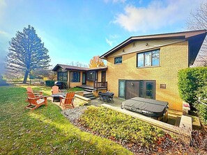 Une maison à deux étages dotée d’un patio aménagé avec des meubles d’extérieur et un barbecue.
