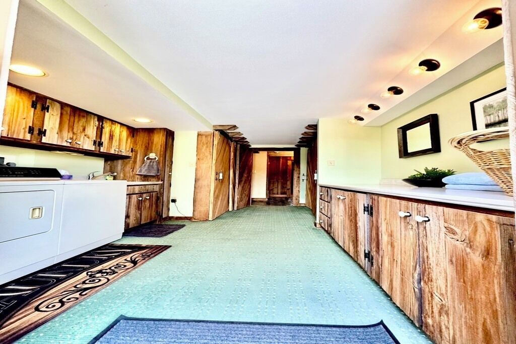 A narrow hallway with wooden cabinets, a white countertop, and a patterned rug.