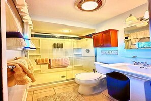 Une salle de bain avec une douche à parois de verre, des toilettes, un lavabo et une poubelle.