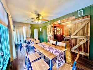 Un espace repas avec des tables et des chaises en bois, un ventilateur de plafond et un mur en bois rustique.