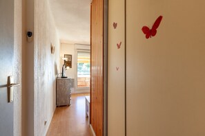 Un pasillo con una puerta de madera, una lámpara de pared y un ventanal con persianas.