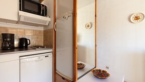 A kitchen with a microwave, refrigerator, coffee maker, and a dishwasher.