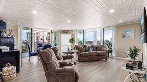 A spacious living area with a wooden ceiling, large windows, and modern furniture.