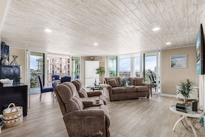 A spacious living area with a wooden ceiling, large windows, and modern furniture.