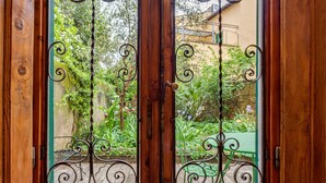 A wooden door with a metal gate and a view of a garden with a green table and plants. - Apartment 'La Casa Vintage' with Private Garden, Wi-Fi and Air Conditioning (Firenze)