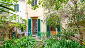 A courtyard with a table and chairs, a wooden door, and a garden with various plants. - Apartment 'La Casa Vintage' with Private Garden, Wi-Fi and Air Conditioning (Firenze)