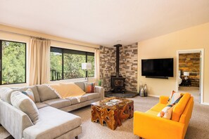 Una sala de estar con un sofá modular, un sillón naranja brillante, una mesa de centro y una chimenea.
