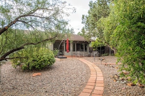 Un patio techado con un sendero de ladrillo que conduce a una casa.