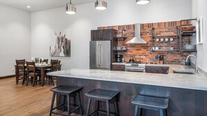 A modern kitchen with a brick backsplash, stainless steel appliances, and a central island with bar stools. - New! Downtown Whitefish with private hot tub and balcony (Whitefish)