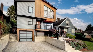 Une maison à deux étages avec un garage, un balcon et un petit garage attenant.