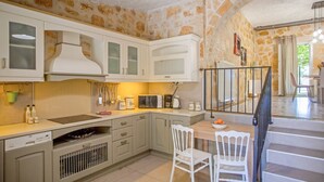 A kitchen with white cabinets, a wooden table, and a white chair. - Your Luxury Escape in Corfu’s Tranquil Countryside (Akrokefalo Gouvia)