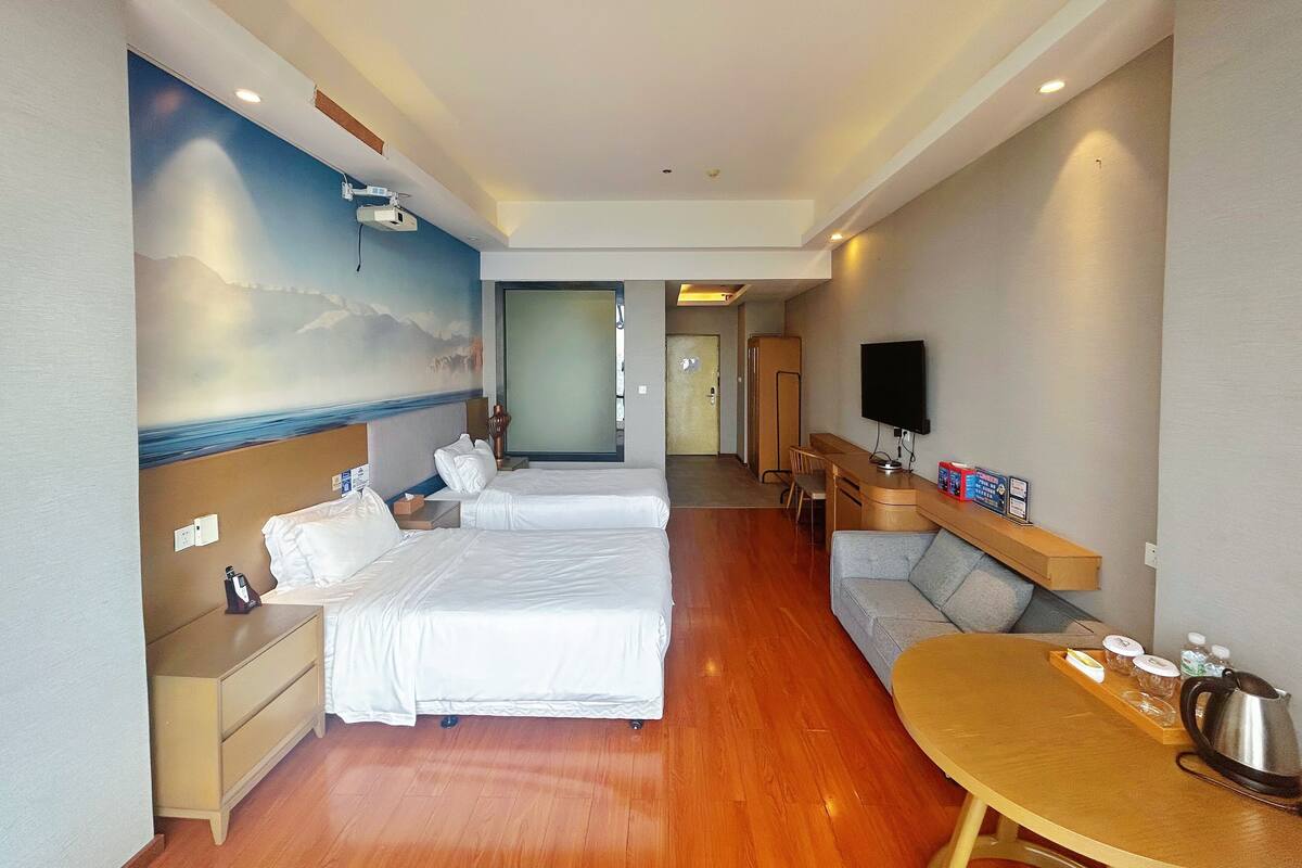 Een hotelkamer met twee bedden, een bureau, een televisie en een eettafel.