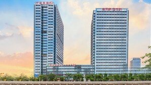 A modern high-rise building with a unique L-shaped design, featuring multiple floors and a glass facade.