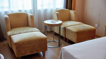 Relax in a serene space with a large bed, two armchairs, and a small table.