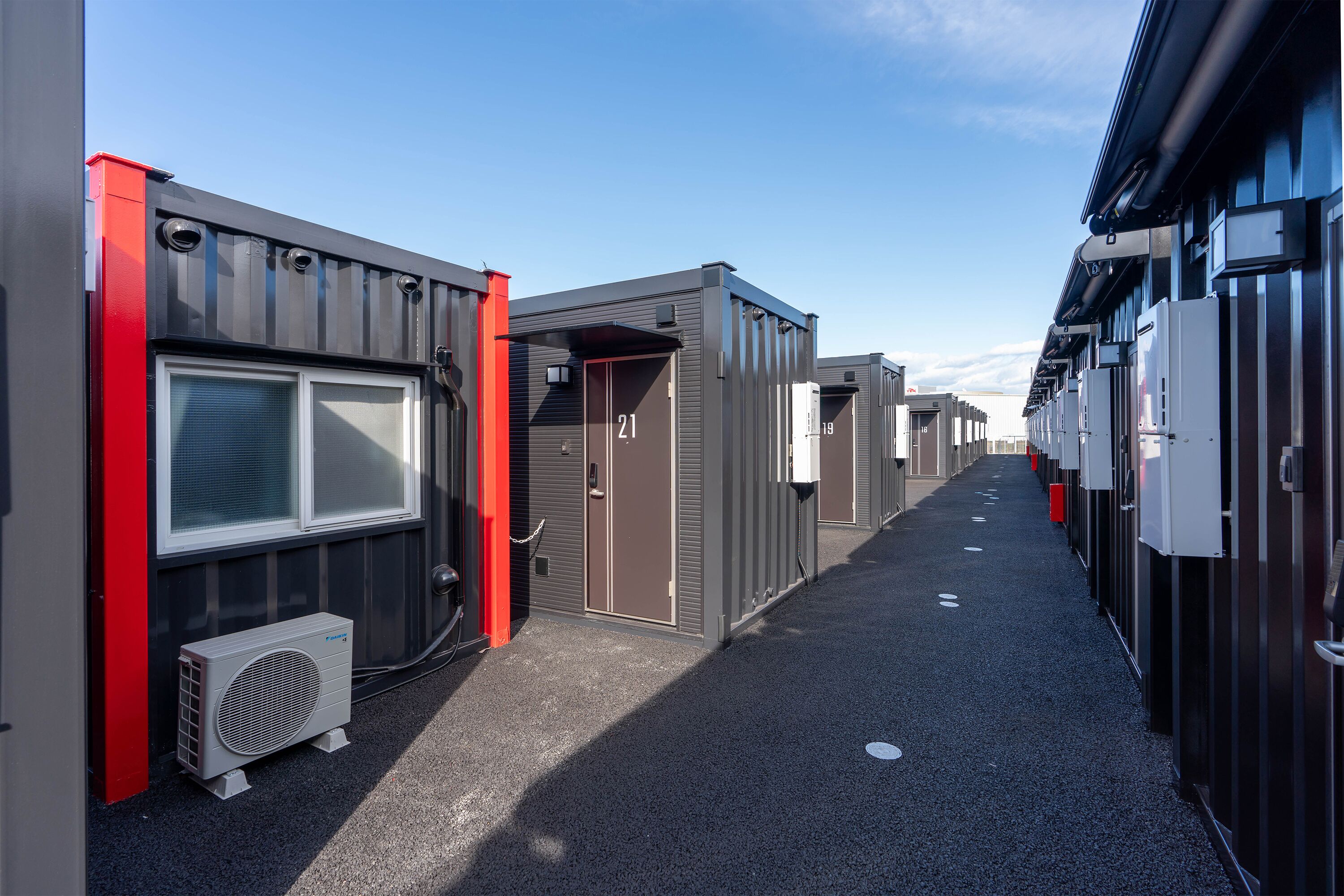 A row of compact, modern buildings with numbered doors, likely indicating individual units or rooms.