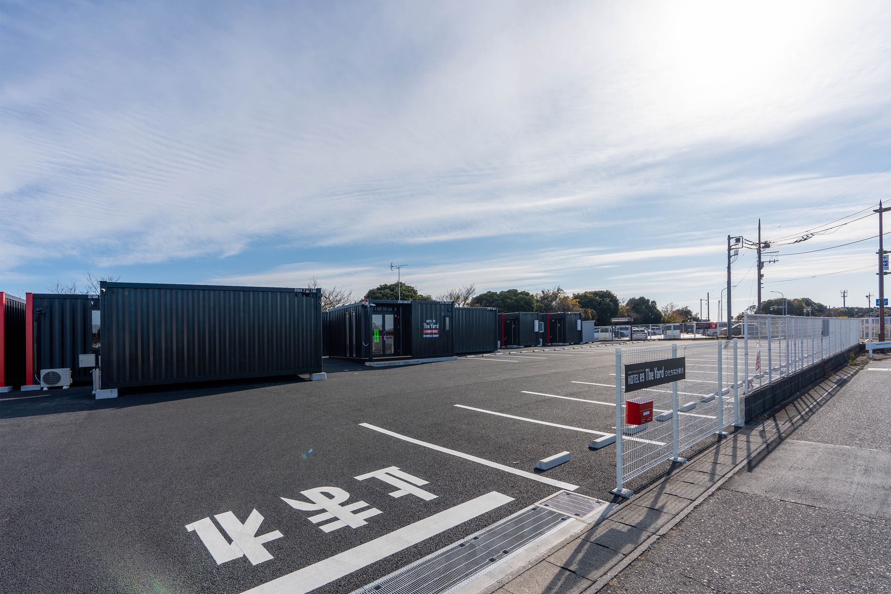 A parking lot with shipping containers and a fenced area.