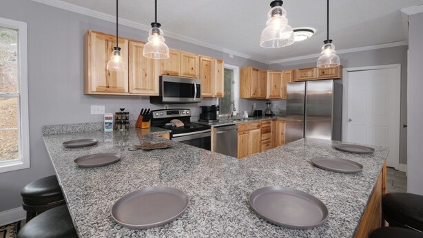 A modern kitchen with granite countertops, wooden cabinets, stainless steel appliances, and pendant lighting. - Hot Tub Soaks Under the Stars, Firepit S'mores & Secluded Mountain Vibes - A Country Retreat (Gatlinburg)