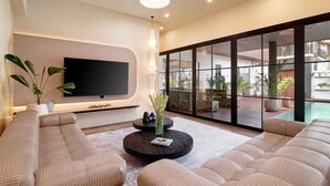 A modern living room with a sectional sofa, a round coffee table, and a flat-screen TV mounted on the wall.