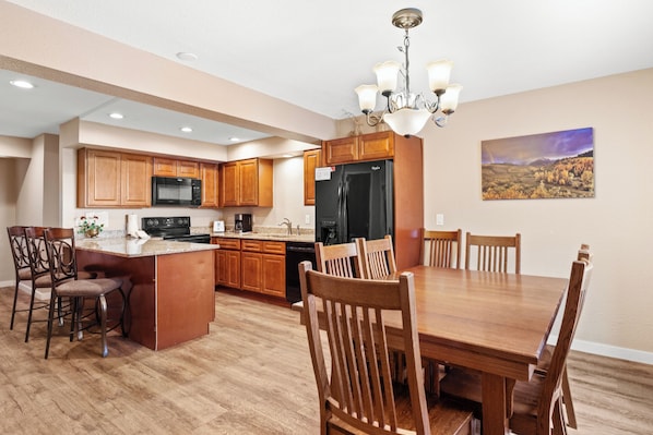 Una cocina amplia con armarios de madera, una isla central y un comedor con una gran mesa y sillas de madera.