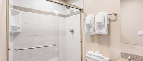 A modern bathroom with a glass-enclosed shower, a toilet, and a sink with a granite countertop.