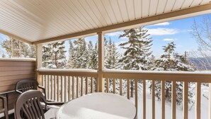 A covered outdoor area with a table and chairs, overlooking a snowy landscape with trees. - Rr49b3 (Breckenridge)