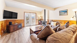 A living room with a wooden cabinet, a flat-screen TV, a sofa, and a fireplace. - Rr49b3 (Breckenridge)