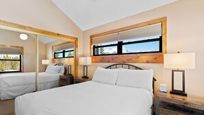 Ein Hotelzimmer mit einem großen Bett, zwei Nachttischen, einem Spiegel und einem Fenster mit Blick auf die Berge.