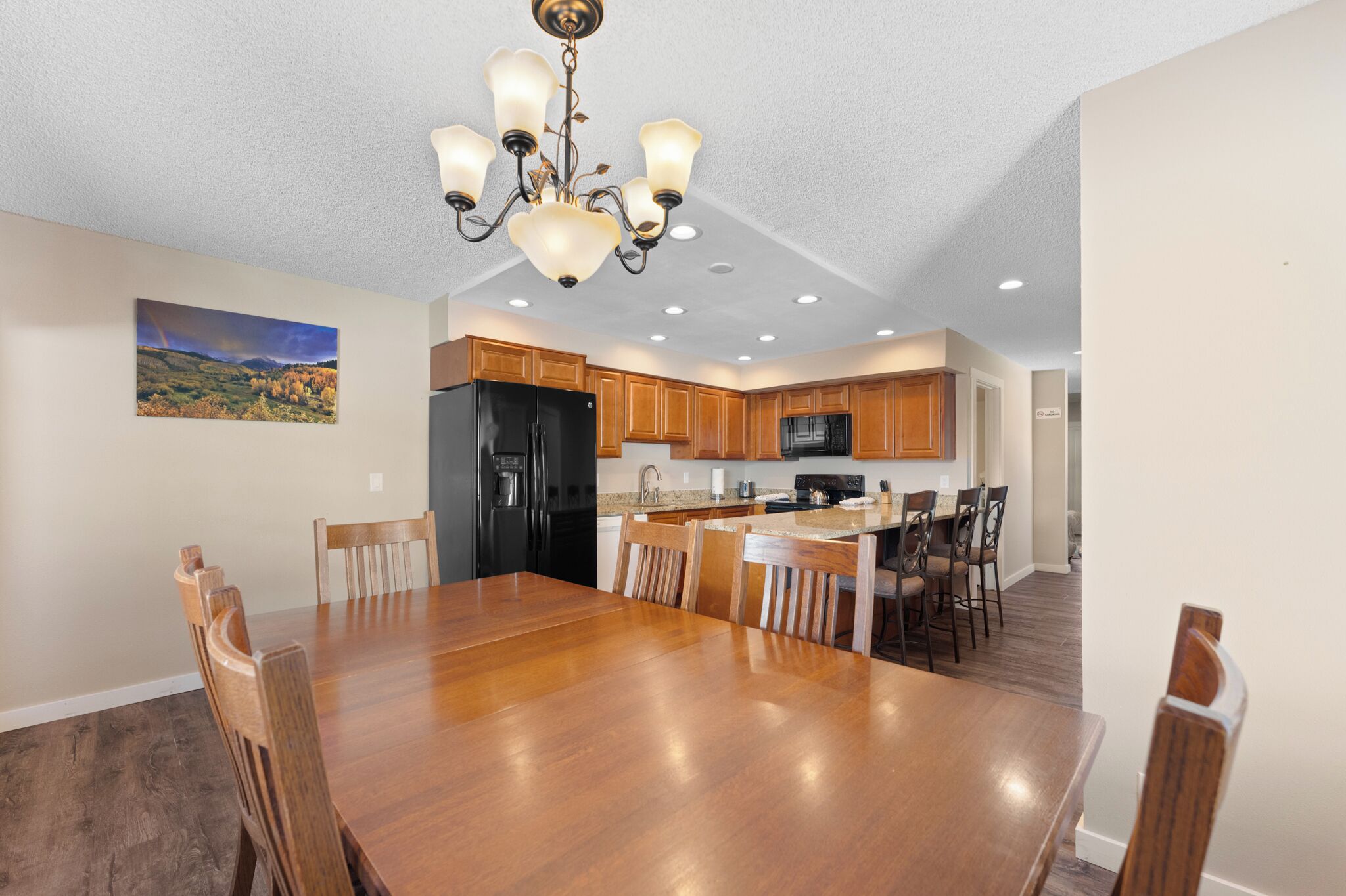 A spacious kitchen with wooden cabinets, a central island, and a dining area with a large wooden table and chairs.