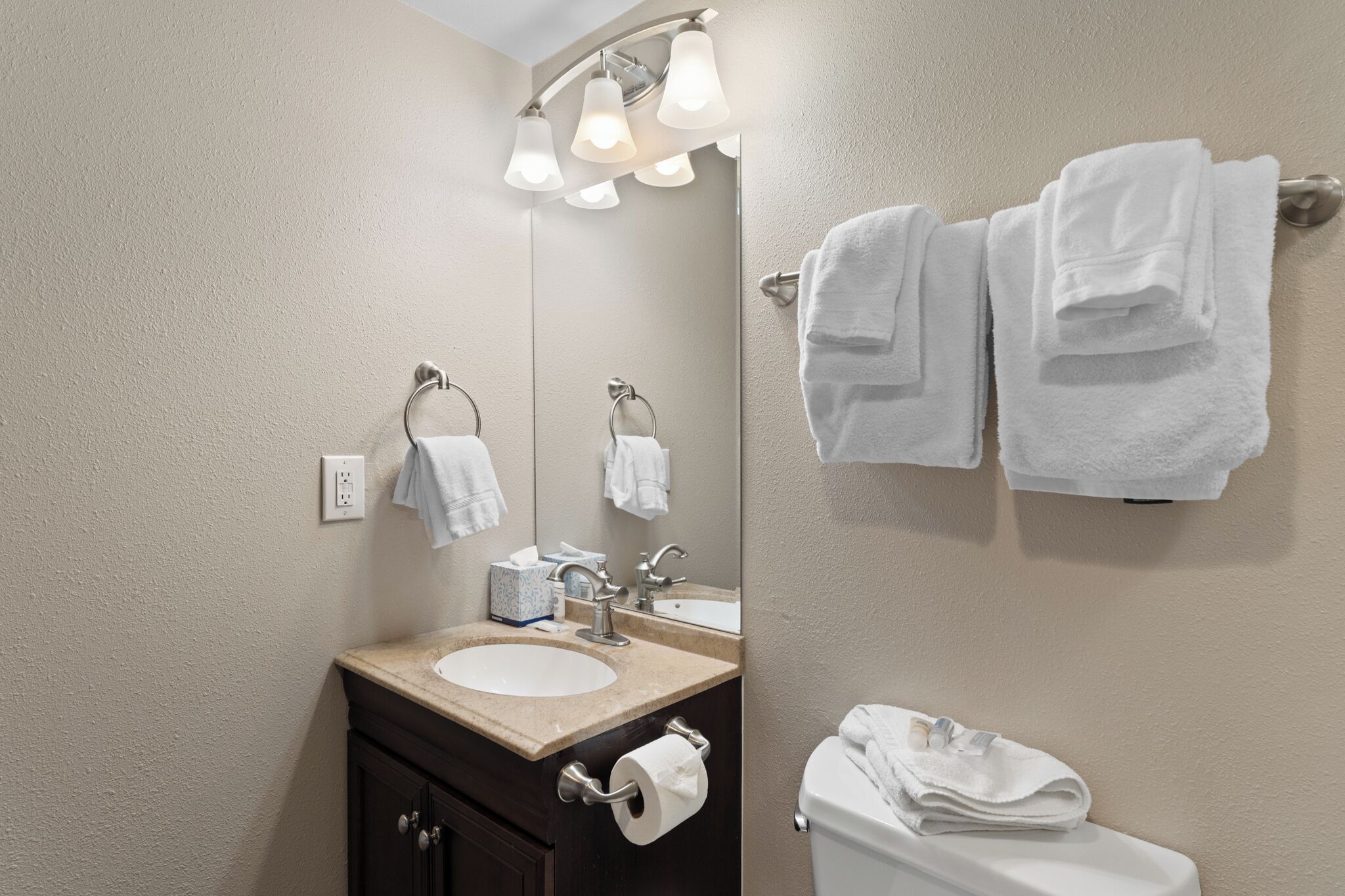 Ein Badezimmer mit Waschbecken, Spiegel, Handtuchhalter und Toilette.