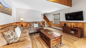 A spacious living room with a wooden ceiling, a sofa set, a coffee table, a TV, and a staircase. - Rr59b3 (Breckenridge)