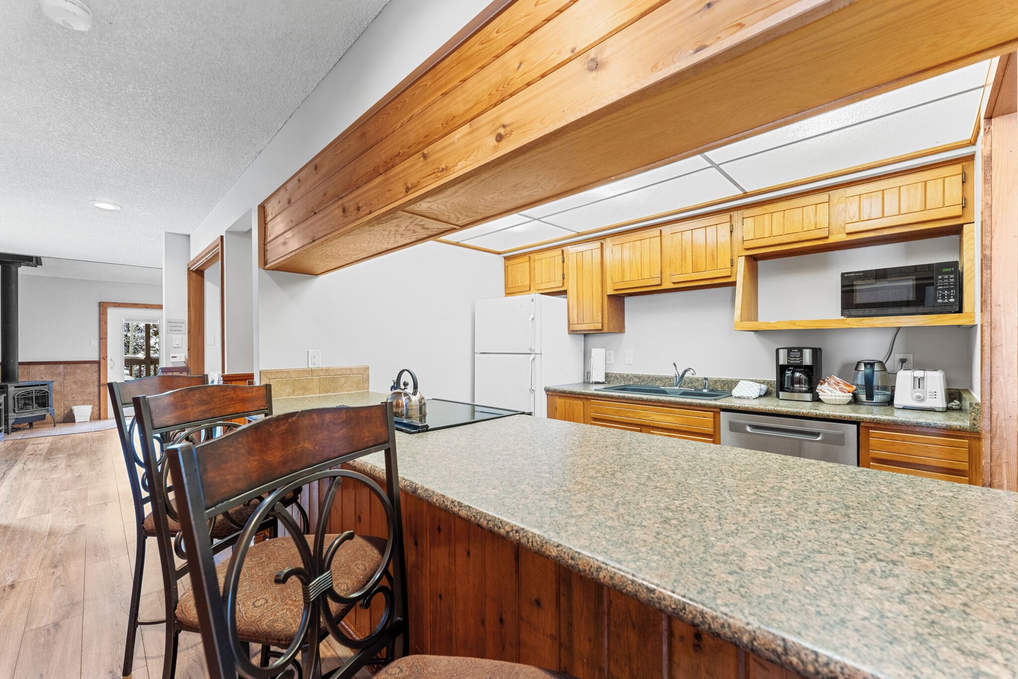 Cocina moderna con armarios de madera, encimeras de granito y electrodomésticos de acero inoxidable.