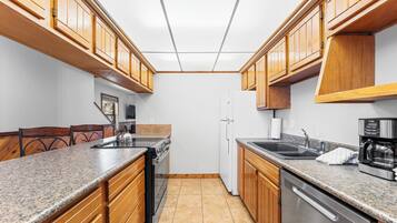 Eine Küche mit Holzausstattung, Granitarbeitsplatten, einem Edelstahl-Geschirrspüler und einem eingebauten Backofen.