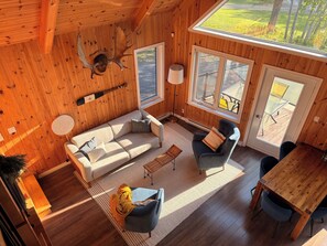 Ein gemütliches Blockhaus-Interieur mit einer Couch, einem Sessel und einem Esstisch.