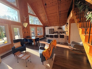 A spacious cabin interior with a dining area, kitchen, and a staircase.