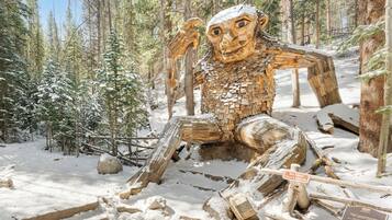 Une sculpture représentant une figure humaine, située dans un décor de forêt enneigée.