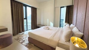 Ein modernes Hotelzimmer mit einem großen Bett, einem Nachttisch, einer Lampe und Blick auf die Stadt durch große Fenster.
