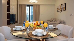 Ein moderner Essbereich mit einem Glastisch, gedeckt für das Frühstück, mit Croissants, Früchten und Orangensaft.