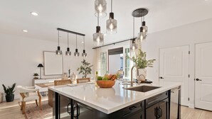 A modern kitchen with a large island, pendant lights, and a view into the dining area. - Luxe Two Story Condo in the Heart of Downtown SB! (Santa Barbara)