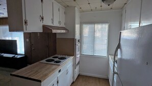 A compact kitchen with white cabinets, a stove, and a refrigerator. - Heavenly Gates (South Lake Tahoe)