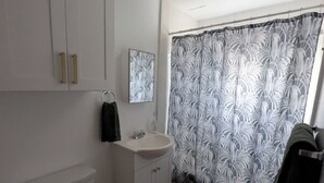 A bathroom with a toilet, sink, cabinet, and shower curtain. - Heavenly Gates (South Lake Tahoe)