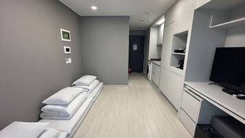 A hotel room with a bed, a TV, a washing machine, and a small kitchenette.