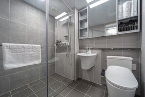 Une salle de bain moderne avec une douche en verre, un lavabo, des toilettes et un porte-serviettes sur lequel est posée une serviette portant l’inscription « Bella Stay Chuncheon ».