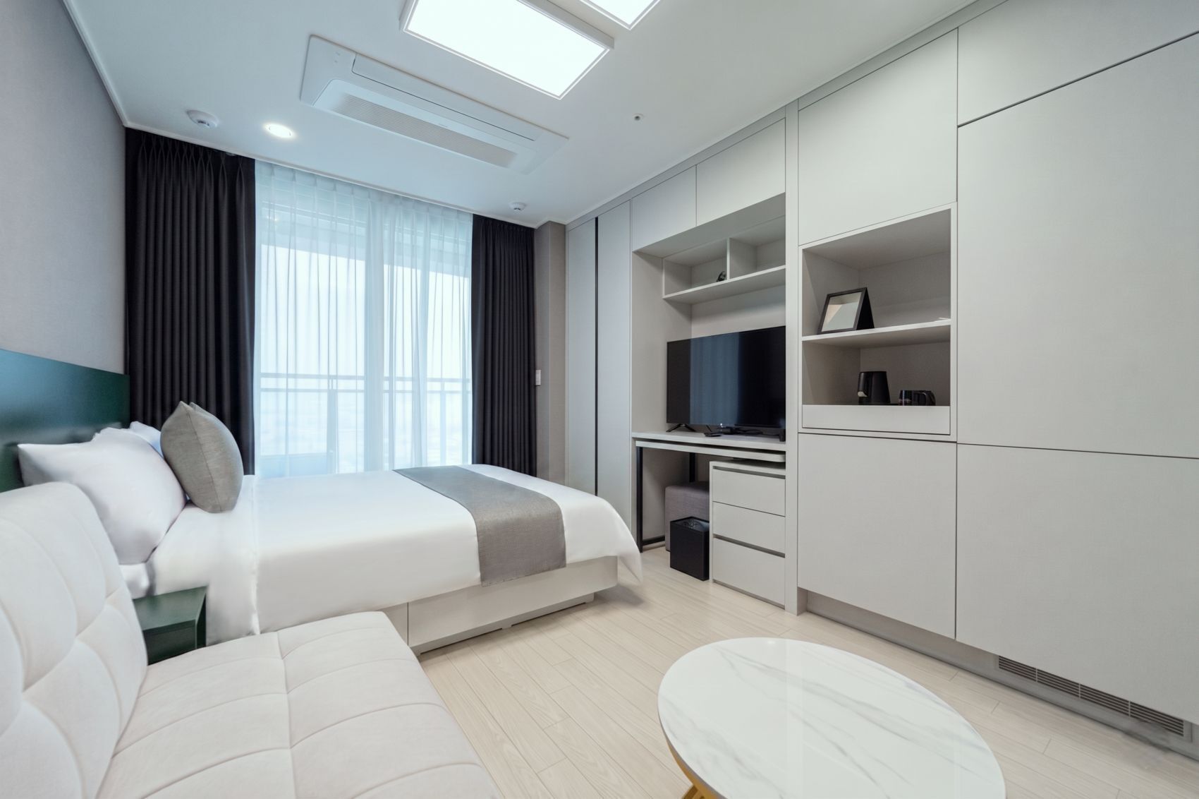 Una habitación de hotel moderna con cama, escritorio, televisor y zona de estar.