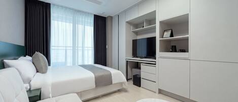 Una habitación de hotel moderna con cama, escritorio, televisor y zona de estar.