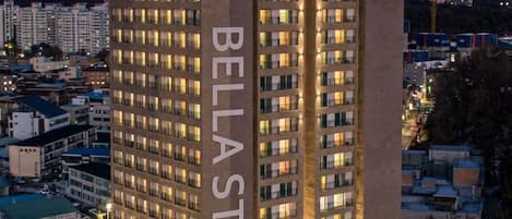 A multi-story hotel with a prominent 'Bella Stay' sign, featuring a modern architectural design with a flat roof and numerous windows.