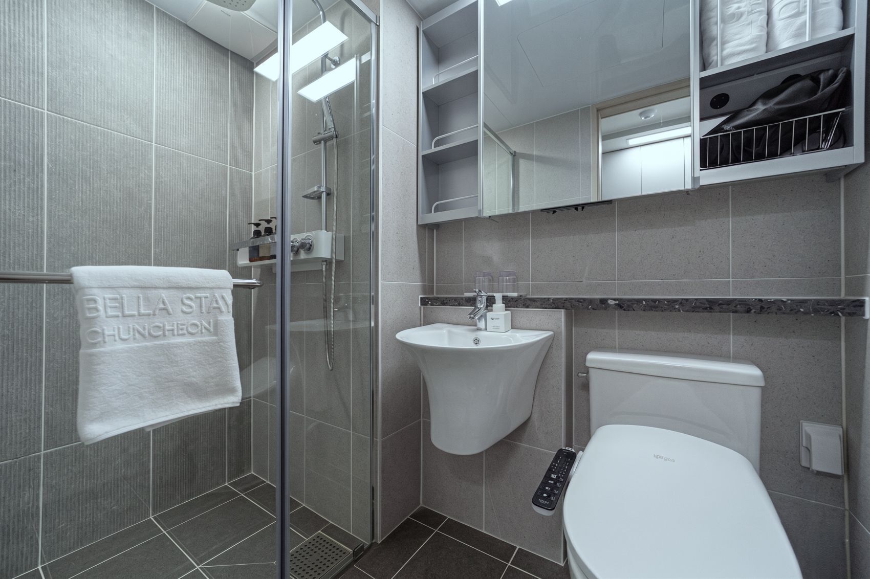 A modern bathroom with a glass-enclosed shower, a white sink, and a toilet.