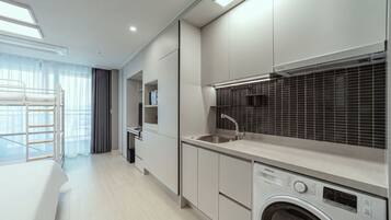 A modern kitchen with built-in appliances, a washing machine, and a dining area with a bunk bed.